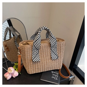 Détail du sac cabas en paille beige avec poignée décorée d'un foulard rayé noir et blanc