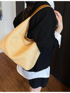 Large woven straw tote bag with brown leather trim and shoulder strap for beach holidays