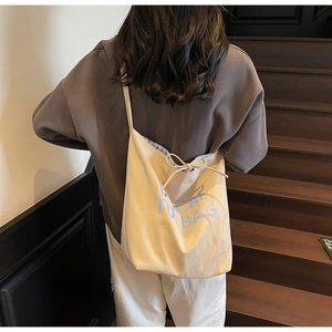 Détail du sac cabas en toile beige avec imprimé TUCAT BAG et doublure à carreaux bleus