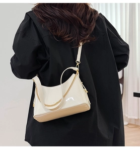 Detailed back view of a chic cream white patent leather bucket bag with gold chain strap