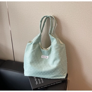 Detail of mint green canvas tote bag with textured dots and woven brand tag