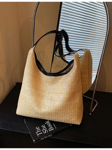Large beige woven straw tote bag with black leather trim for summer beach vacations