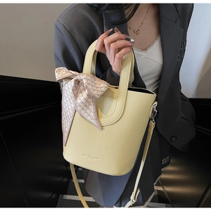 Dettaglio borsa a secchiello gialla con grana litchi, foulard in seta e tracolla