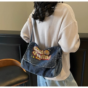 Detail of vintage washed denim crossbody bag with embroidery and adjustable strap