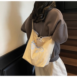 Détail d'un sac cabas en toile avec cordon de serrage et lettres imprimées bleues