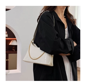 Detail of white patent leather tote bag with gold chain strap and luxury glossy finish