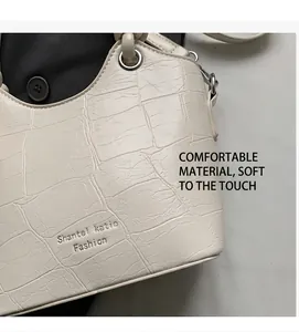 Detail of cream crocodile pattern tote bag with embossed logo and metal hardware