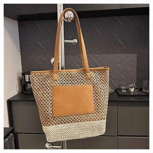 Detail of a large woven tote bag featuring bicolor straw texture and leather handles