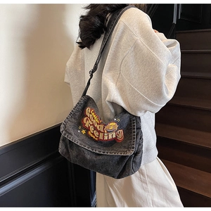 Close-up of vintage washed denim tote with vibrant Looking Good Feeling Good embroidery