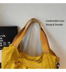 Detail of sturdy yellow nylon tote bag handles and reinforced stitching for durability