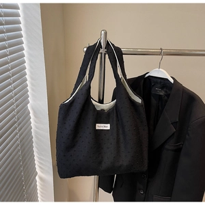 Detail of black tote bag featuring textured polka dot fabric and Nuo si Man brand label