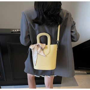 Dettaglio della borsa a secchiello gialla in pelle martellata con foulard e tracolla