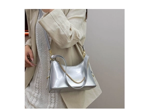 Detailed shot of silver shiny bucket bag with golden chain and adjustable strap