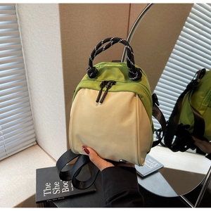 Detail of avocado green and beige shell backpack with woven handle and dual zippers
