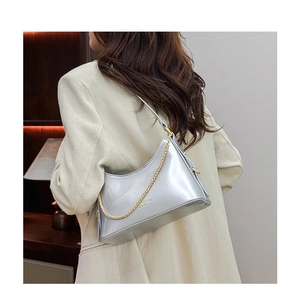 Detail of silver mirror hobo bag with gold chain strap and brand logo on leather
