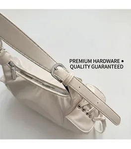 Gros plan des finitions métalliques argentées haut de gamme sur un sac à bandoulière crème