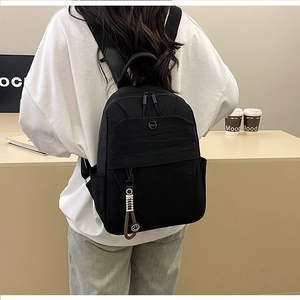 Detail of black nylon minimalist backpack featuring a circular NMC logo and smiley charm