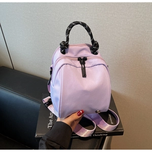 Detail of light purple waterproof nylon backpack featuring black and white cord handles