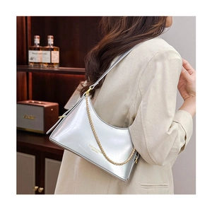 Detail of silver metallic shoulder bag featuring gold chain strap and mirror finish