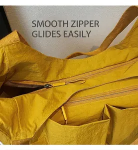 Detail view of smooth double zipper closure on a yellow nylon crossbody bag