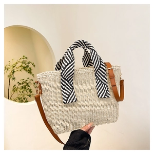 Détail du sac de plage tissé avec poignée en foulard rayé et bandoulière en cuir brun