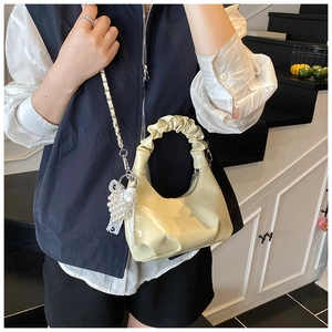 Détail du sac coquille jaune avec poignée plissée, pendentif perle et chaîne en métal
