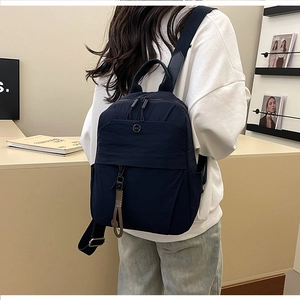 Model wearing a minimalist dark blue nylon backpack with NMC logo for daily commuting