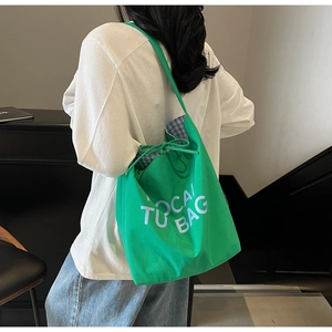 Détail du sac cabas en toile verte avec lettrage blanc et fermeture à cordon