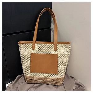 Detail of woven straw tote bag featuring brown faux leather straps and a dual-texture design