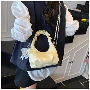 Detailed view of yellow shell bag with ruched handle and large pearl bow charm
