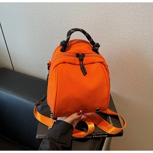 Close-up of orange waterproof nylon shell bag with woven handle and nylon strap