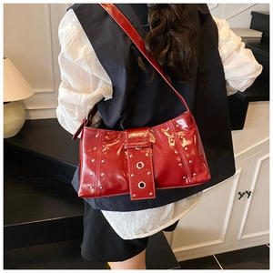 Détail d'un sac à bandoulière en cuir verni rouge avec clous et boucle décorative