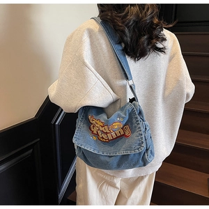 Detail of light blue denim tote with vintage American style embroidery and adjustable strap