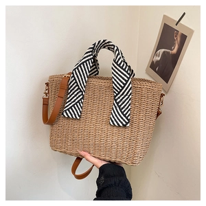 Détail du sac cabas en paille tissée avec poignée foulard rayée et bandoulière en cuir