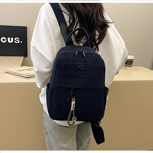 Detail of navy blue nylon backpack with HMC logo and trendy smiley charm on model