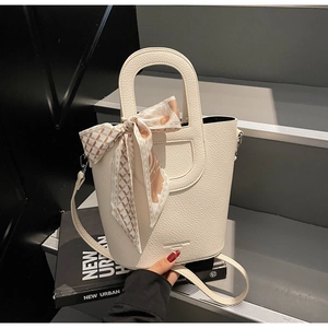 Dettaglio della borsa a secchiello in pelle beige con foulard di seta decorativo