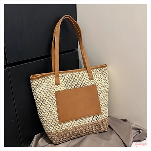 Detail of woven straw tote bag featuring leather handles and a front pocket design