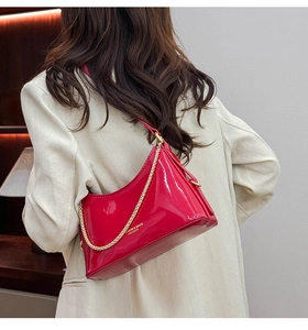Close-up of bright red patent leather bucket bag with gold chain and fashion lettering