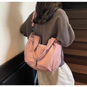 Pink large capacity nylon tote bag shown on shoulder in a casual lifestyle scene