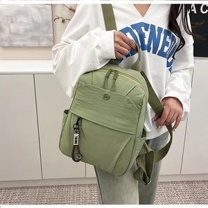 Close-up of grass green nylon backpack with NMC logo and stylish woven charm