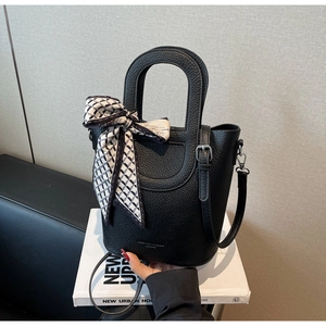 Dettaglio della borsa a secchiello nera con grana litchi, foulard e tracolla