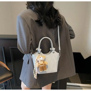 Detail of light blue crocodile texture bucket bag with cute bear charm and knotted handle