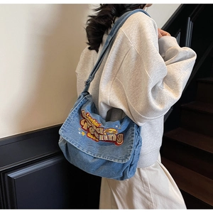 Detail of vintage blue denim bag with colorful 'Lookin' Feeling Good' embroidery