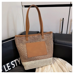 Detail of two-tone woven straw tote bag with brown leather handles and textured finish