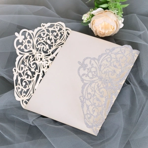 Detail of laser-cut wedding invitation with cream white pearlescent paper and silver glitter