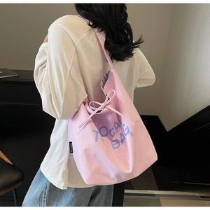 Détail du cabas en toile rose avec lettrage bleu, nœud décoratif et doublure à carreaux