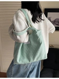 Light green canvas tote bag with polka dot texture shown on shoulder of a model