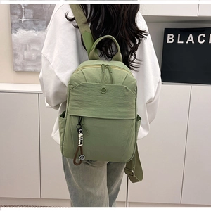 Detail of lightweight green nylon backpack with front zipper pocket and side water bottle holder