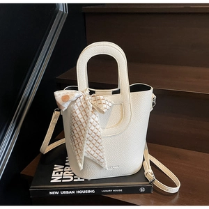 Dettaglio borsa a secchiello bianco crema con trama litchi e foulard di seta geometrico