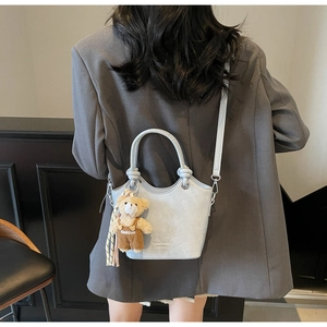 Detail of light blue crocodile pattern bucket bag with a cute plush bear charm